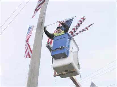  ?? Contribute­d photo ?? Brian Locke places an American flag in one of more than 120 telephone pole mounts in Brookfield in honor of Memorial Day. The Jason D. Lewis Brookfield Memorial VFW Post this year took over the tradition of hanging American flags along sections of Route 25, Route 133 and Long Meadow Hill Road. Greg Waldmiller, a retired Brookfield patrolman and now a special officer with the Brookfield Police Department, started the tradition 18 years ago.