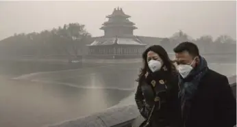  ?? KEVIN FRAYER/GETTY IMAGES ?? A couple wear protective masks as they walk outside the Forbidden City on a day of heavy pollution in Beijing.