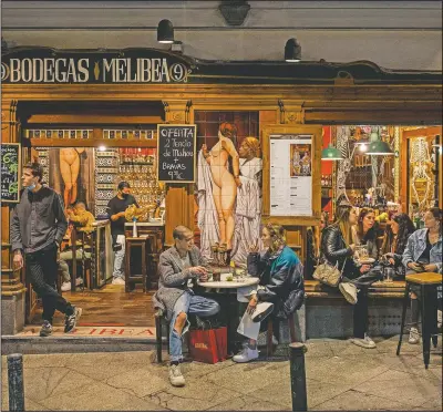  ?? (AP/Bernat Armangue) ?? Tourists and locals have drinks at a bar in downtown Madrid.