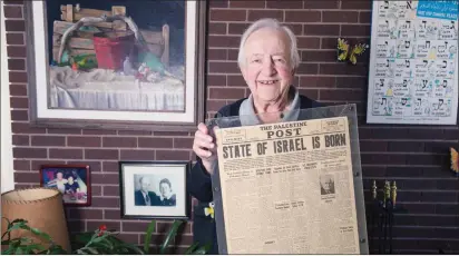  ?? TAPLIN/THE CHRONICLE HERALD ?? Nevo holds up a treasured piece that isn’t one of his own. The front page of The Palestine Post on May 16, 1948 declares the State of Israel is born. The paper would change its name in 1950 to The Jerusalem Post.