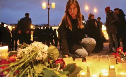  ?? YEVGENY KURSKOV, THE ASSOCIATED PRESS ?? A woman lights a candle at an entrance to Sennaya subway station after an explosion Monday in St. Petersburg. Eleven were killed and more than 40 hurt.