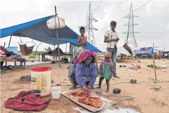  ??  ?? HARD LIFE: Left, A woman washes clothes at a makeshift shelter in Ahmedabad.