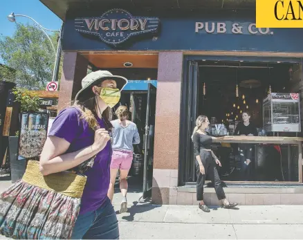  ?? PETER J THOMPSON/NATIONAL POST ?? Pedestrian­s pass a pub in Toronto, as the city prepares to allow indoor bar and restaurant service despite concerns it will fuel COVID clusters.