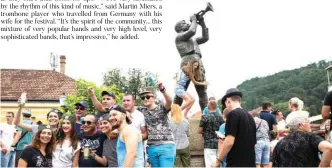  ??  ?? Festival-goers pose for pictures in front of the trumpeter statue in the city center during the trumpet and brass band festival in the Serbian village of Guca, about 160 km (100 miles) south of Belgrade.