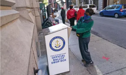  ?? Photograph: David Goldman/AP ?? Eva Abodoadji drops off a mail ballot into an official ballot drop box in Providence, Rhode Island, on 14 October.