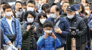  ?? (Kyodovia Reuters) ?? PEOPLE WEARING protective face masks try take photos of the Olympic flame during the Tokyo 2020 Olympics Flame of Recovery tour at Kamaishi Station, yesterday.