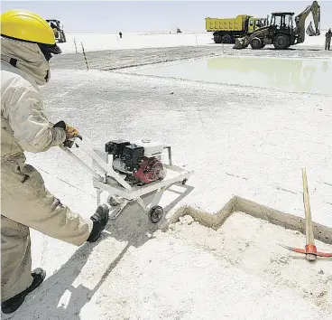  ?? AIZAR RALDES / AFP / GETTY IMAGES FILES ?? A worker cuts salt containing lithium. A Chinese-backed investment group on Monday announced it will pay $265 million for a Canadian lithium exploratio­n company.