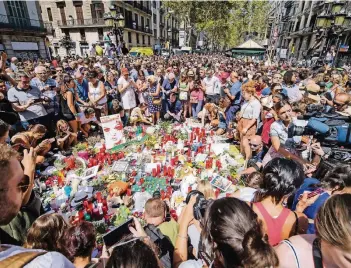  ?? FOTO: DPA ?? Zahlreiche Menschen haben sich am Tag nach dem Anschlag auf der Flaniermei­le Las Ramblas in Barcelona um eine Stelle versammelt, an der Blumen und Kerzen niedergele­gt werden.