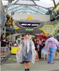  ??  ?? MY FAVORITE PICTURE at Universal Studios Singapore, wearing a packable poncho like some of the people behind me. My poncho kept me dry from the heavy rains and unpredicta­ble splashes at Jurassic Park Rapids Adventure.