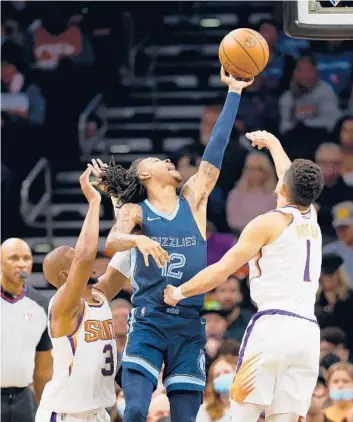  ?? CHRISTIAN PETERSEN/GETTY ?? The Grizzlies’ Ja Morant attempts a shot over the Suns’ Devin Booker, right, and Chris Paul on Dec. 27.