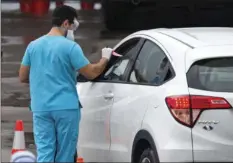  ?? VIA AP
DAVID SANTIAGO/MIAMI HERALD ?? Vehicles line up as a healthcare worker helps to check in as citizens is being tested at the COVID-19 drive-thru testing center at Hard Rock Stadium in Miami Gardens on Sunday.