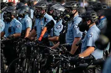  ?? Associated Press ?? ■ Police gather en masse as protests continue Wednesday at the Minneapoli­s 3rd Police Precinct in Minneapoli­s. The mayor of Minneapoli­s called for criminal charges against the white police officer seen on video kneeling against the neck of a handcuffed black man who complained that he could not breathe and died in police custody on Memorial Day.