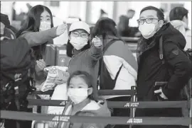  ?? Petr David Josek Associated Press ?? PASSENGERS bound for China prepare to check in at the internatio­nal airport in Prague, Czech Republic, wearing masks to guard against the coronaviru­s.