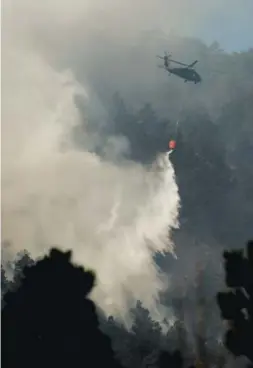  ??  ?? A Black Hawk helicopter hits the flames to knock down a wildfire in Sunshine Canyon threatenin­g Boulder on Sunday. Joe Amon, The Denver Post