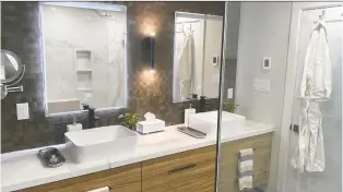  ?? THE HOLMES GROUP ?? A layered lighting approach is the best way to illuminate any bathroom, big or small. Mike Holmes used a combinatio­n of natural light, pot lights, vertical wall sconces and LED mirrors in his recent bathroom renovation to create a bright and airy space.