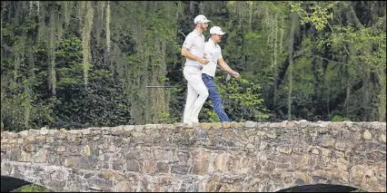  ?? CURTIS COMPTON / CCOMPTON@AJC.COM ?? Dustin Johnson (front) and Brooks Koepka cross the Nelson Bridge on the 13th fairway during Wednesday’s practice round. Johnson may not be crossing the bridge again this week.