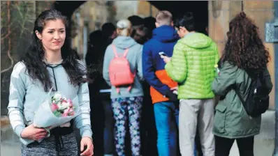  ?? TOLGA AKMEN / AGENCE FRANCE-PRESSE ?? A student carries flowers as others queue to sign a book of condolence at Cambridge University’s Gonville and Caius College, where British physicist, Stephen Hawking was a fellow for more than 50 years. Hawking died on Wednesday, aged 76.