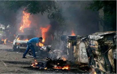  ?? AP ?? A man lifts a motorbike in an area vandalised by Dera Sacha Sauda sect members in Panchkula on Friday. —