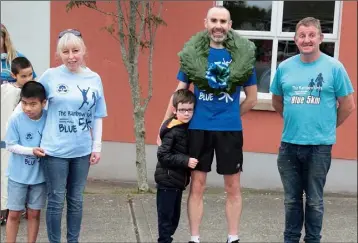  ??  ?? Ky Busher, Mary Ryan and Billy Morris making a presentati­on to Tommy Walsh, and his son Daniel, after Tommy finished his 500km run in aid of the Rainbow Unit at Scoil Mhuire.
