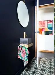  ??  ?? LEFT TO RIGHT Midnight-hued walls, patterned tiles and gold tapware give this small powder room a strong presence. Teal wall tiles work with the multicolou­red Moroccan rug in this bathroom. A custom concrete and timber vanity makes a statement.