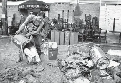  ?? AMY DAVIS/BALTIMORE SUN PHOTOS ?? Workers clean out mud and debris from the Phoenix Emporium at 8049 Main St. On Sunday, one week after the devastatin­g flood, Howard County workers escorted storekeepe­rs, business owners and residents to their properties for a “recovery day.”