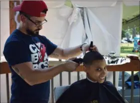  ?? BRIANA CONTRERAS — THE MORNING JOURNAL ?? Edsel Sanchez, a student barber from Lorain, provides free haircuts to youngsters and adults alongside other local barbers and those of Headlinerz Barbershop in Lorain during the fourth annual SoberFest at Oakwood Park in Lorain on Aug. 4.