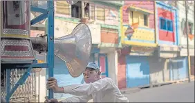  ??  ?? A man pushes a cart mounted sound system, used for weddings and other celebratio­ns, past closed stores on a deserted street during corona curfew in Moradabad, on Tuesday.