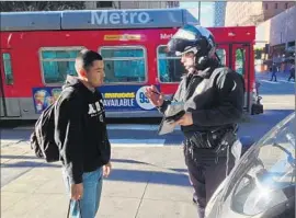  ?? Catherine Saillant
Los Angeles Times ?? EDUARDO LOPEZ gets a citation from Officer Robert Lockhart, who said he had warned Lopez not to cross. Lopez said he didn’t hear him.