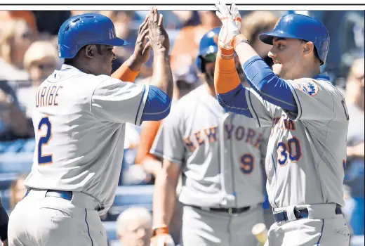  ??  ?? CELEBRATE GOOD TIMES: Michael Conforto (right) celebrates with Juan Uribe after hitting a two-run home run during the second inning of the Mets’ 10-7, 10-inning victory over the Braves.