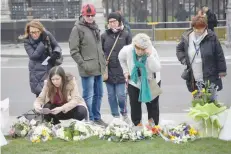  ??  ?? Members of the public lay flowers and pay their respects at Parliament Square in Westminste­r on the anniversar­y of the Westminste­r Bridge attack in London on Thursday. — Reuters