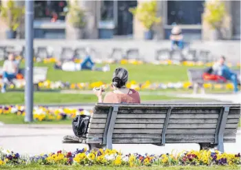  ?? FOTO: MARIJAN MURAT/DPA ?? Immerhin: Einzeln auf einer Parkbank zu sitzen, wie diese Frau in Stuttgart, ist in Baden-Württember­g noch erlaubt. In Bayern braucht es dazu triftige Gründe.