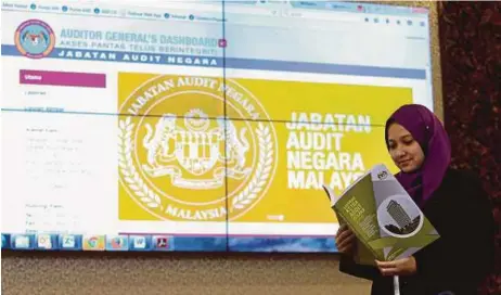  ?? [FOTO MUHD ZAABA ZAKERIA/BH] ?? Pegawai Audit Negara, Siti Zulaiha Mustapar menunjukka­n buku Laporan Ketua Audit Negara 2016 di Bangunan Parlimen, semalam.