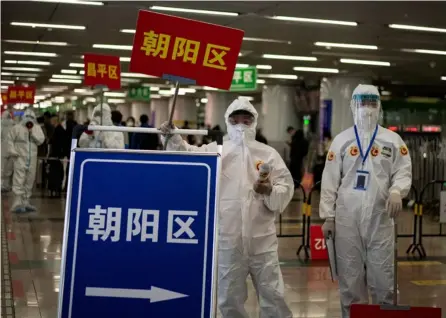  ?? AFP ?? Transporti­stas utilizan trajes de protección mientras esperan a los viajeros que llegan a la ciudad de Wuhan para guiarlos a los autobuses, en la Estación de Ferrocarri­l Oeste de Pekín.