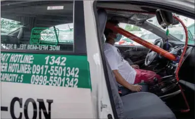  ??  ?? A worker sits inside a taxi with a makeshift barricade for protection against coronaviru­s disease (Covid-19) as taxi operations resume next week, in Quezon City, Metro Manila, yesterday.