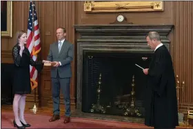  ?? (AP/Collection of the Supreme Court of the United States/Fred Schilling) ?? Chief Justice John Roberts (right) administer­s the judicial oath to Judge Amy Coney Barrett last week in the East Conference Room of the Supreme Court Building as Barrett’s husband, Jesse M. Barrett, holds the Bible.