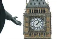  ?? MATT DUNHAM / ASSOCIATED PRESS ?? The hand of a statue of Britain’s World War I Prime Minister David Lloyd George reaches out in the foreground of the Elizabeth Tower at the Houses of Parliament, containing the bell known as “Big Ben” in London.