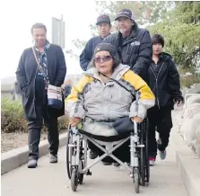  ??  ?? Marlene Bird, centre, is pushed along by friends and family members, who attended the sentencing hearing of Leslie Black, in Prince Albert, Sask., on Friday.