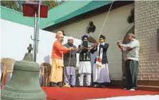  ?? PTI ?? An old bell that was removed is seen in the foreground as people from various faiths ring the new bell at the Holy Family Catholic Church in Srinagar on Sunday.