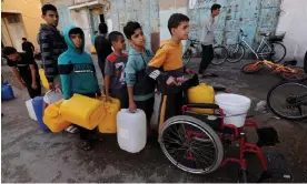  ?? ?? Palestinia­n children wait in a line with containers to collect water, amid drinking water shortages. Photograph: Ibraheem Abu Mustafa/Reuters