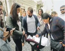  ?? CAROLYN COLE, LOS ANGELES TIMES ?? Baby Mativii was baptized at the Saints Peter and Paul Garrison Church in Lviv, Ukraine, last Sunday. Mother Yaryna Bidyuk, second from left, fled Ukraine to have her baby in Poland due to the war. Her husband, Taras Bidyuk, 25, centre, holding the baby, was serving in the military in Lviv.