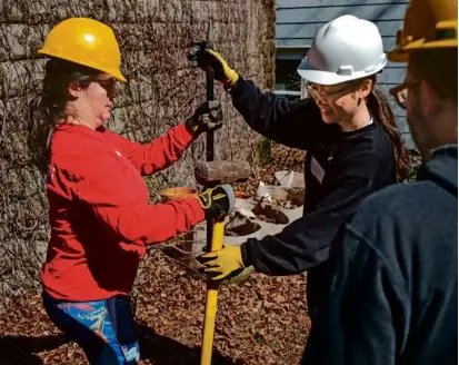  ?? ?? Jen Stevenson Zepeda (in red) demonstrat­ed how to maneuver the asphalt tools to other volunteers. The group’s mission is to bring more green space into Somerville.