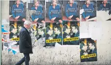  ?? FOTO AFP ?? POPULAR. Un hombre camina por una calle donde se observan afiches de Marine Le Pen y Emmanuel Macron.