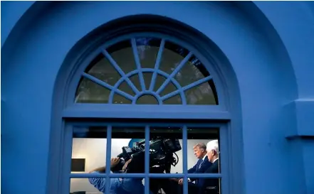  ??  ?? As seen through a window, President Donald Trump speaks during a coronaviru­s task force briefing at the White House.