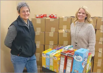  ?? Westside Eagle Observer/DANIEL BEREZNICKI ?? Kelly Hankins (left) and Amanda Kelly (right) organize the food pantry at the Western Benton County Career center building. With the help of their students, they distribute boxes of food that were donated by the Northwest Arkansas Food Bank to family and members of the community. The Highlands United Methodist Church also donated food and supplies.