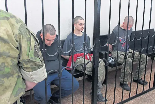  ?? ?? SENTENCED: British citizens Aiden Aslin, left, and Shaun Pinner, right, and Moroccan Saaudun Brahim sit behind bars in a courtroom in Donetsk.