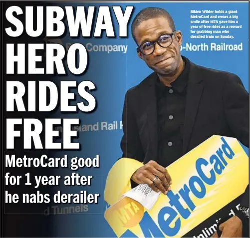  ??  ?? Rikien Wilder holds a giant MetroCard and wears a big smile after MTA gave him a year of free rides as a reward for grabbing man who derailed train on Sunday.