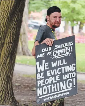  ?? LANCE ANDERSON/TORSTAR ?? Tent City supporter Jeffrey Allan carries a placard around Victoria Park on Tuesday, Aug. 27.