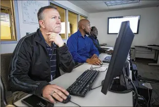  ?? CASEY SYKES PHOTOS / CASEY.SYKES@AJC.COM ?? From left, systems engineers Andy Clement, Corey English and Jerry Thomas, the front line of the DeKalb County school district’s defense against hackers and cyber threats, monitor screens Dec. 6 at the William Bradley Bryant Center for Technology in Decatur.