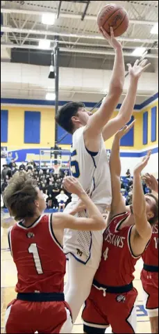  ?? Photo by John Zwez ?? St. Marys Memorial’s Austin Parks shoots over
Wapakoneta’s Taylor Echols (1) and Kaden Siefring (4) during a Western Buckeye League game Friday night in
St. Marys.