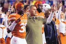  ?? CHUCK BURTON/ASSOCIATED PRESS ?? Texas coach Steve Sarkisian, center, stands with linebacker Devin Richardson (30) as they sing “The Eyes of Texas” after a 57-56 loss to Kansas in overtime Saturday in Austin, Texas.